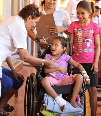 a nurse helping a little girl that is in a wheelchair