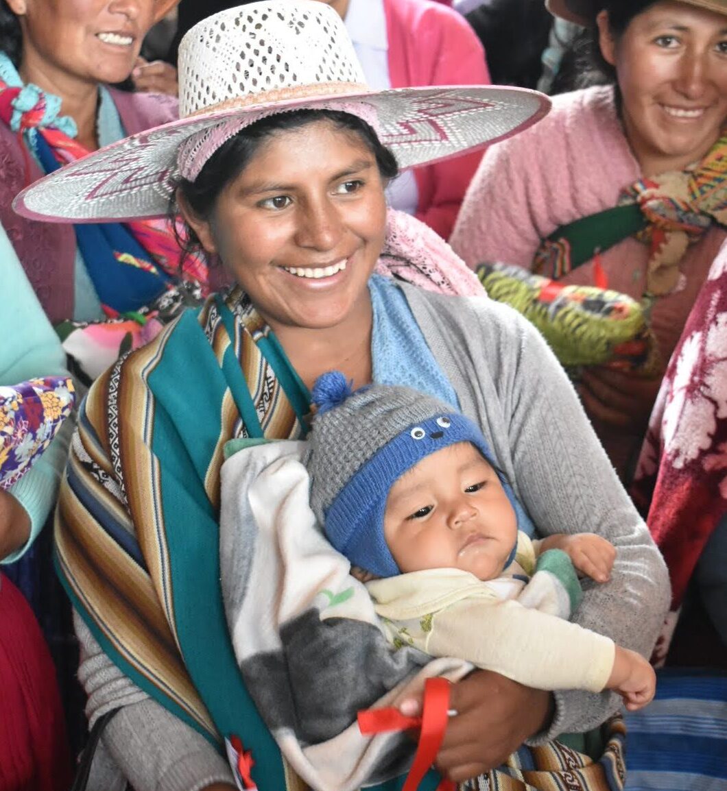 Mother in traditional Bolivian clothing holder her child.