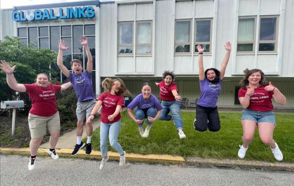 A group of people jumping in front of the Global Links building.